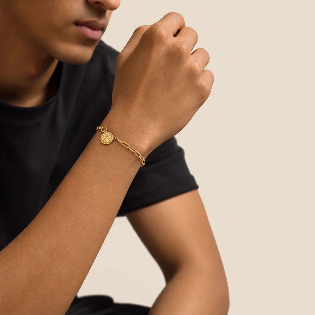 Pulseira cruz de são bento em ouro 18k no pulso, em foto com modelo