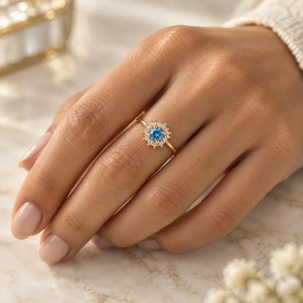 Anel de Ouro com Pedra Azul e Halo em Flor, na mão de uma modelo
