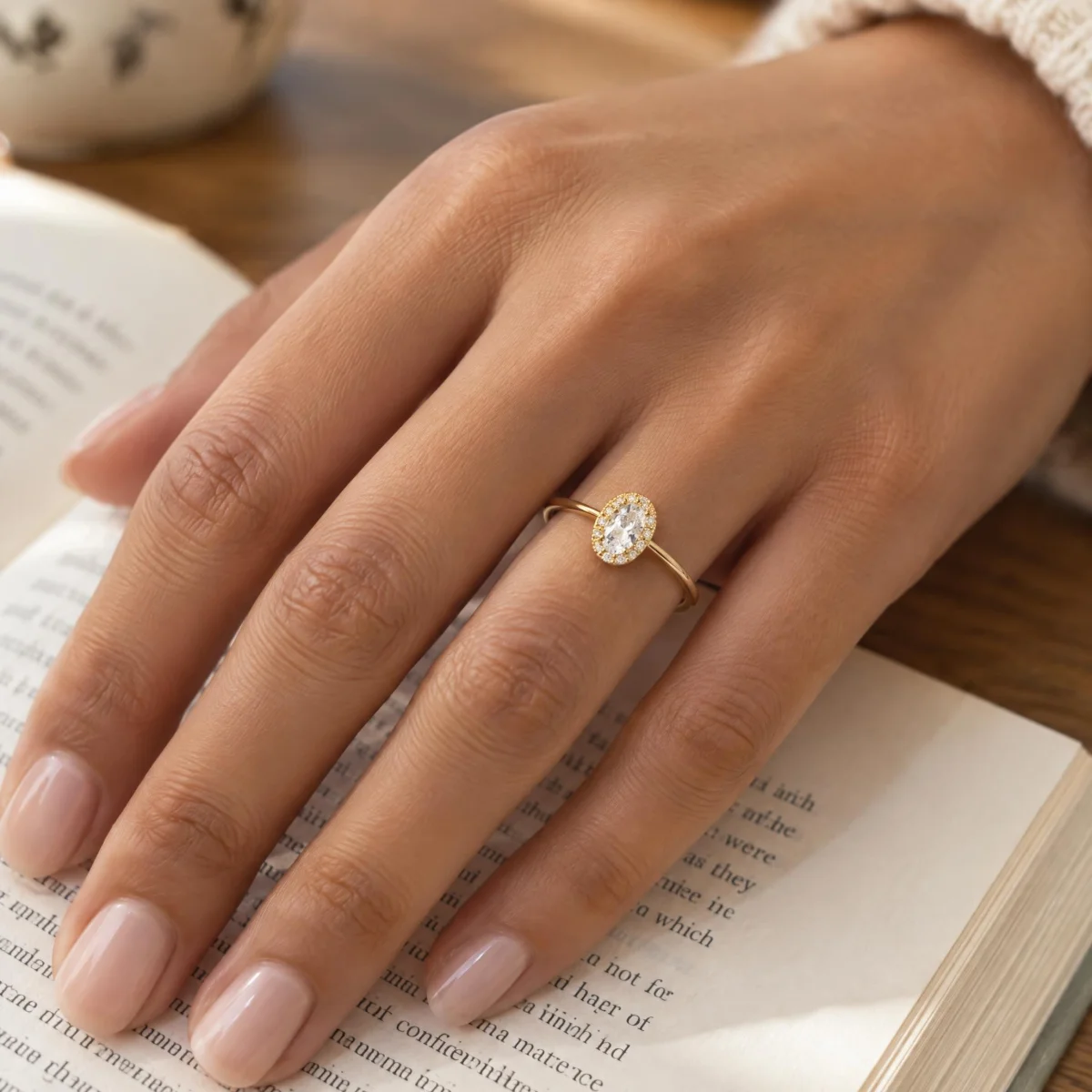 Anel Solitário Oval com Halo de Pedras em ouro 18k, na mão de uma modelo