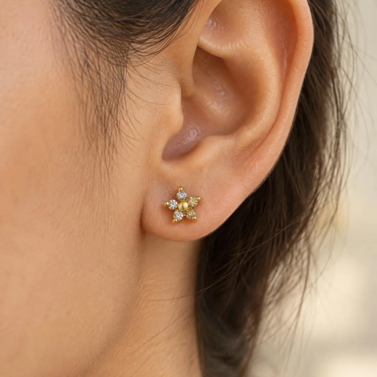 Brinco de Ouro com Zircônia em Flor, na orelha de uma modelo