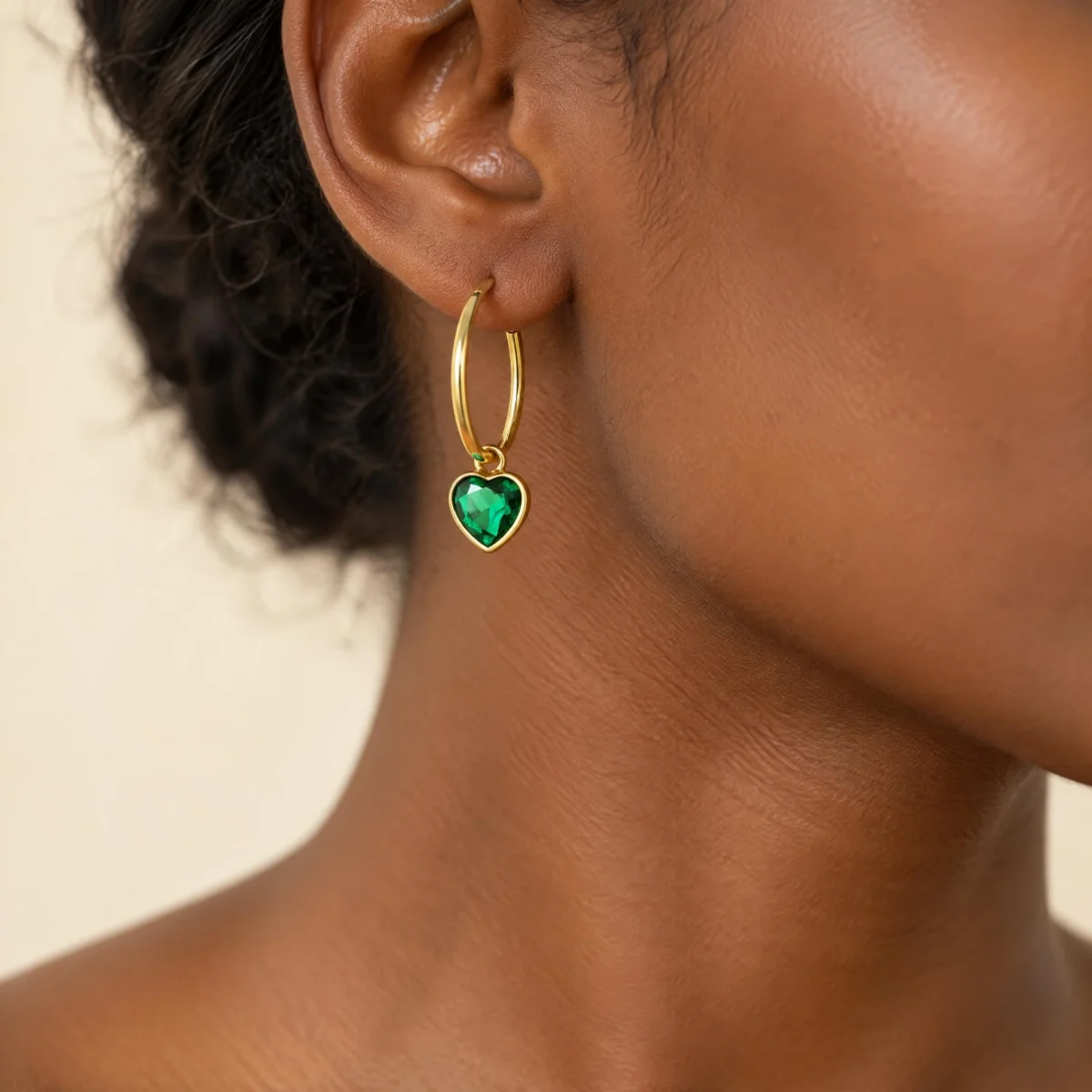Brinco de Pedra Verde em Argola com Coração em ouro 18k, na orelha de uma modelo