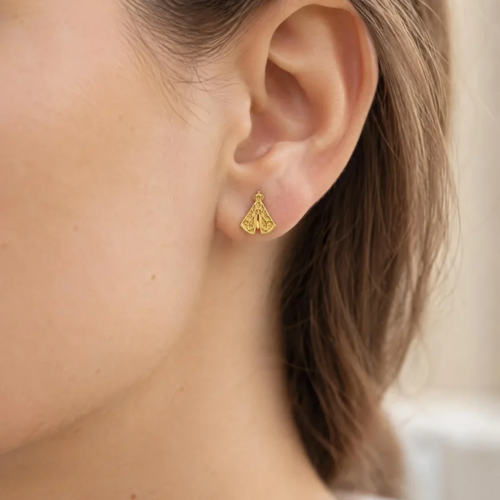 Brinco Nossa Senhora Aparecida Ouro 18k Rendado, na orelha de uma modelo
