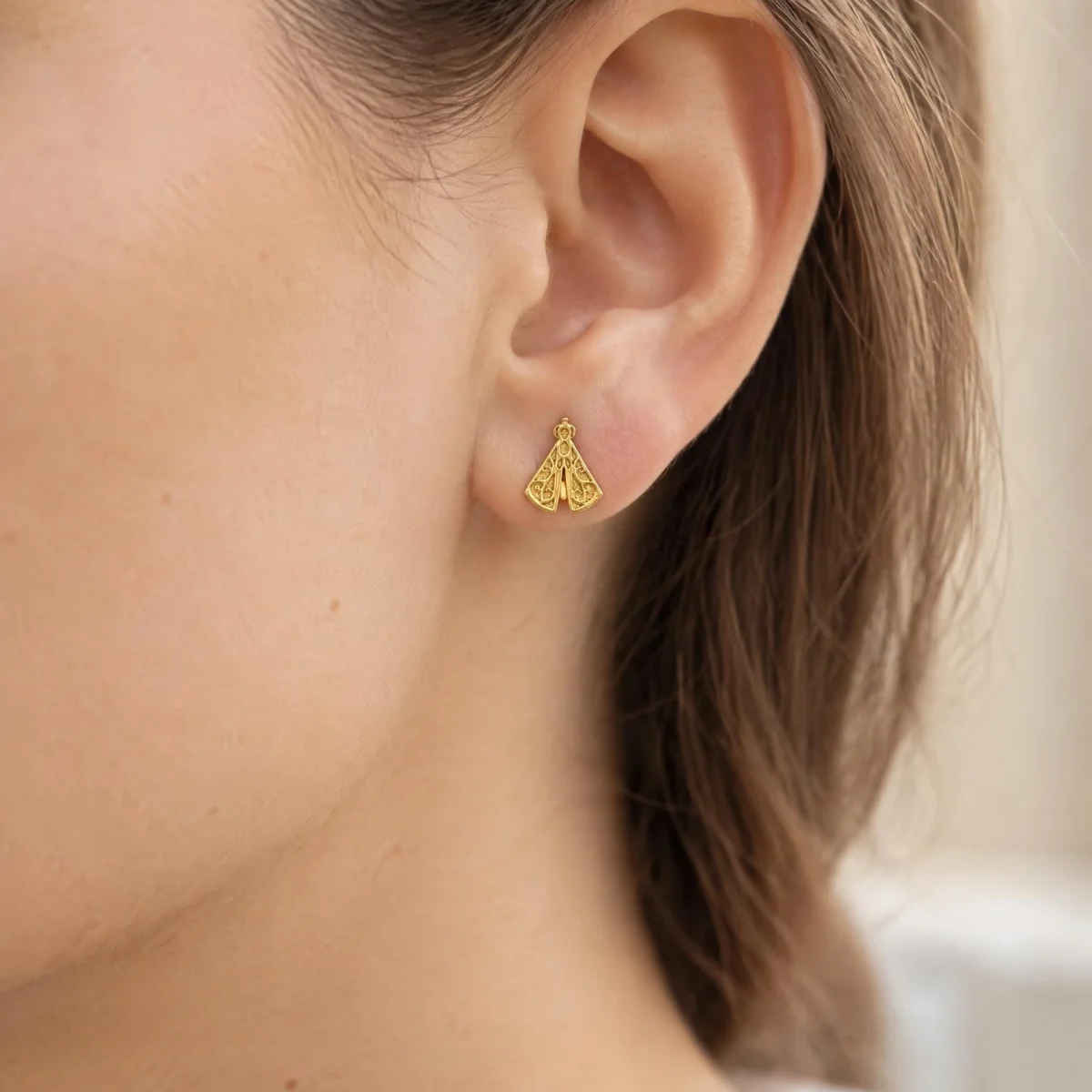 Brinco Nossa Senhora Aparecida Ouro 18k Rendado, na orelha de uma modelo