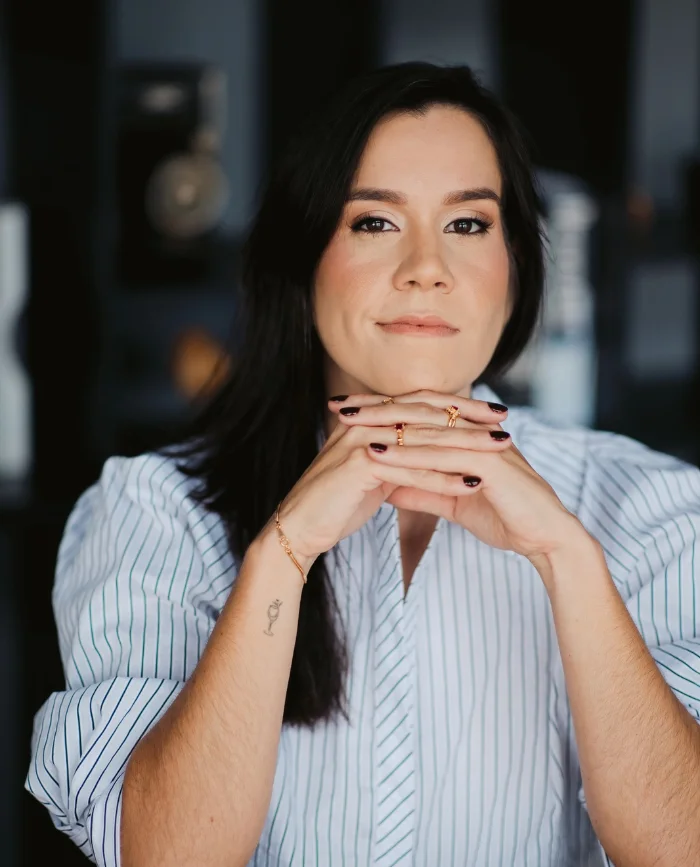Kelly Mar, proprietária da KMS Joias, de camisa listrada com as mãos apoiadas no queixo Kelly Mar, proprietária da KMS Joias, de camisa listrada com as mãos apoiadas no queixo