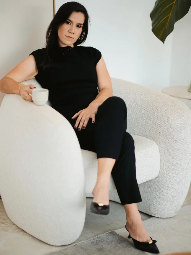 Kelly Mar, proprietária da KMS Joias, sentada em poltrona branca Kelly Mar, proprietária da KMS Joias, sentada em poltrona branca